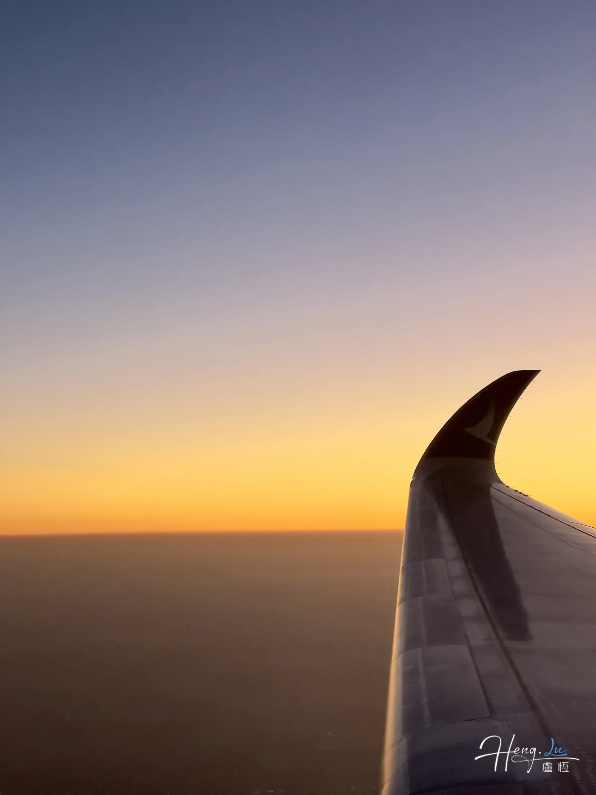 Airplane wing over sunset sky