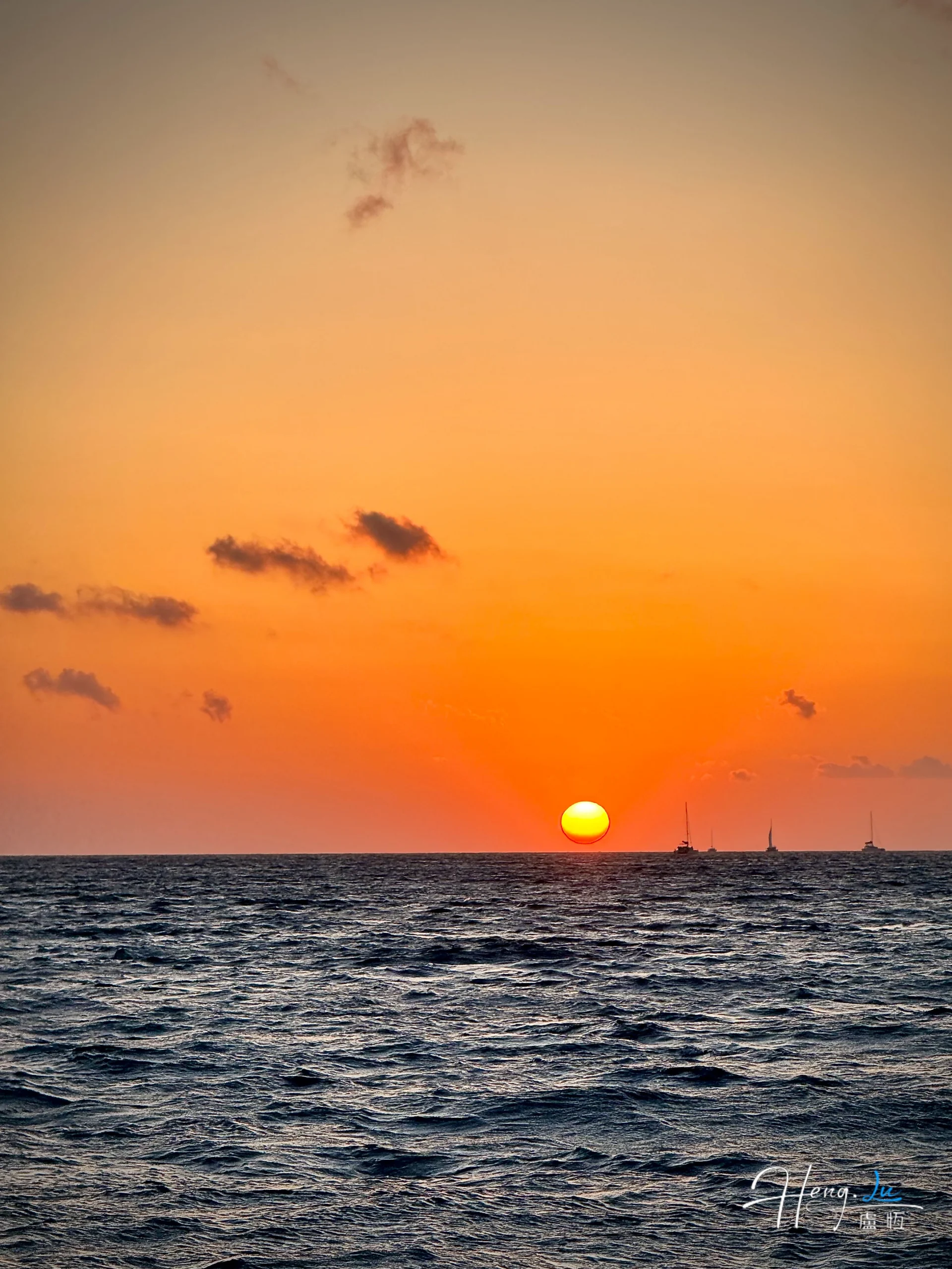 Sunset over ocean with sailing boats