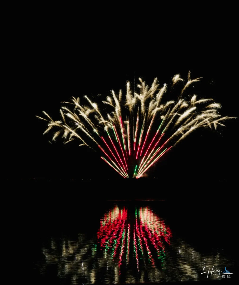 Golden And Red Fireworks Reflect Brightly Over Calm Water