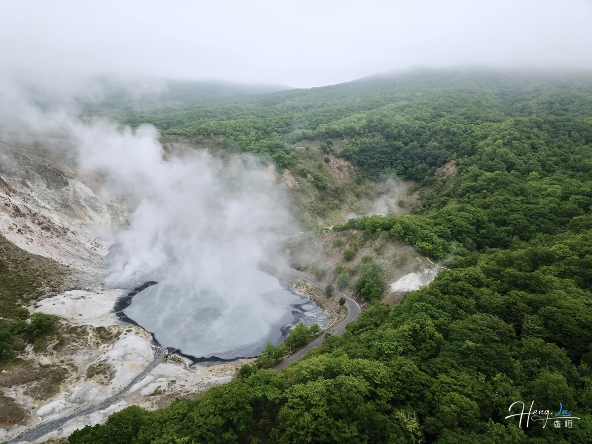 Aerial View Of Steaming Geothermal Valley Surrounded By Forest