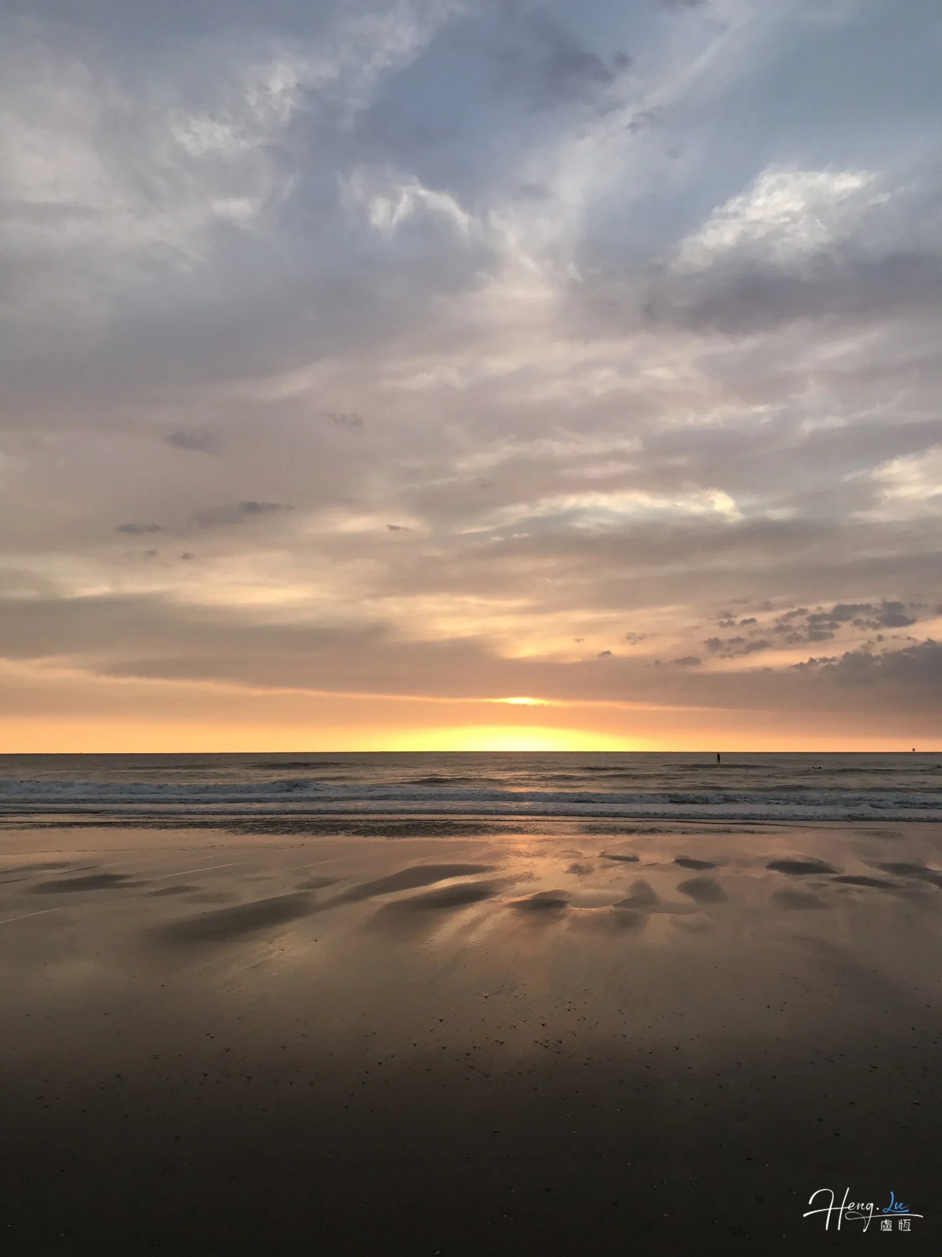 Pastel sunset reflecting on calm beach shore
