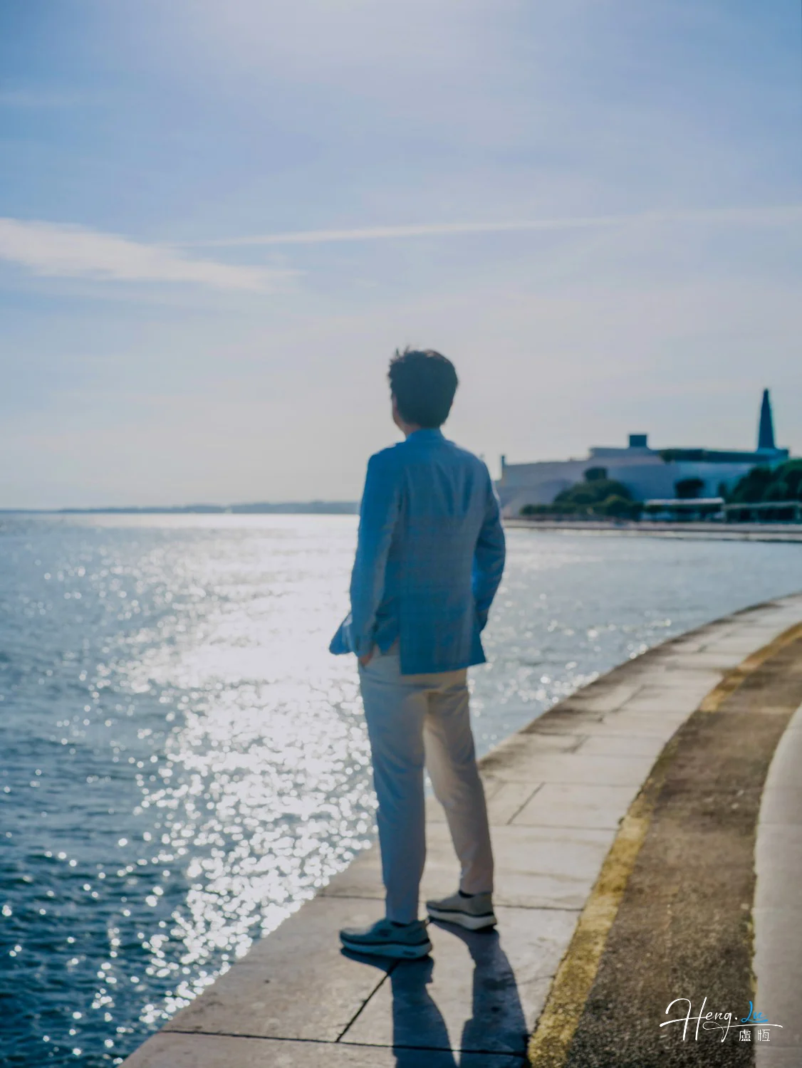 Luheng standing by seaside gazing at sunlit water