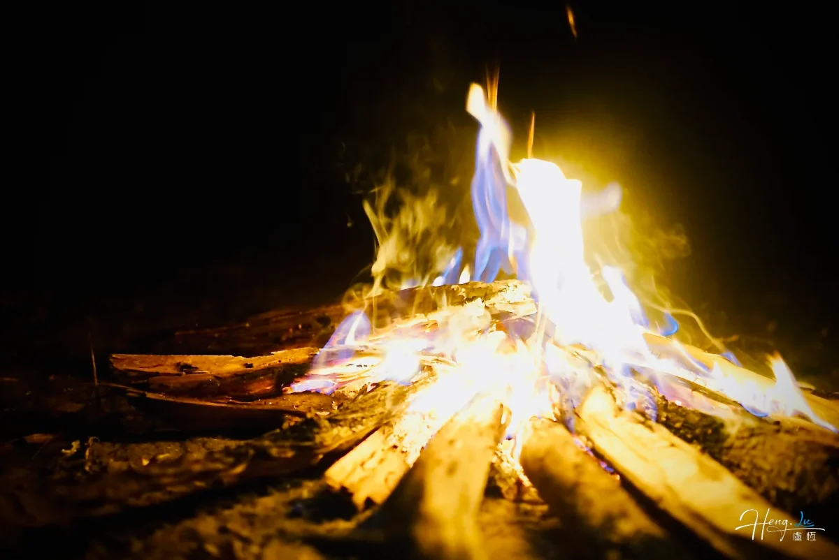 Campfire With Blue And Yellow Flames In Darkness