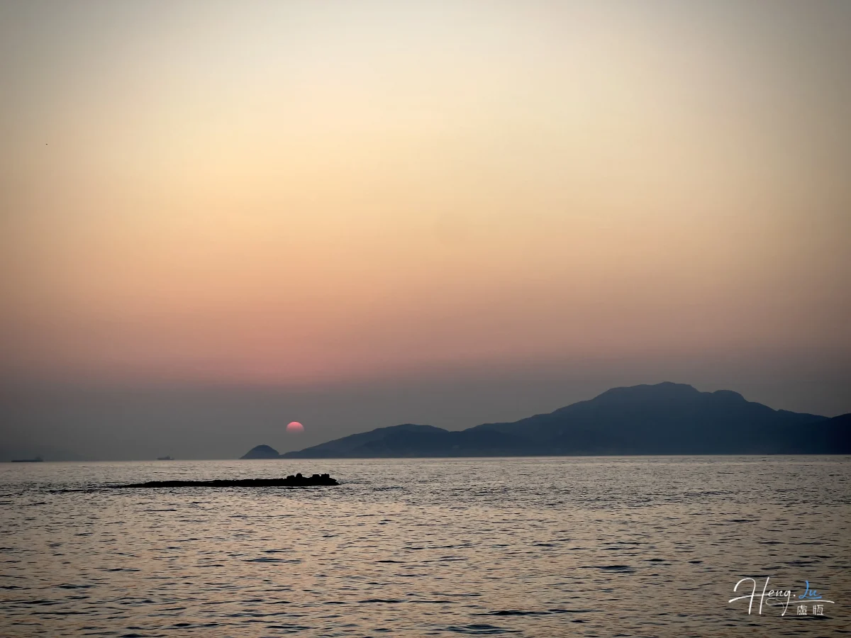 Sunset Over Sea With Distant Mountains