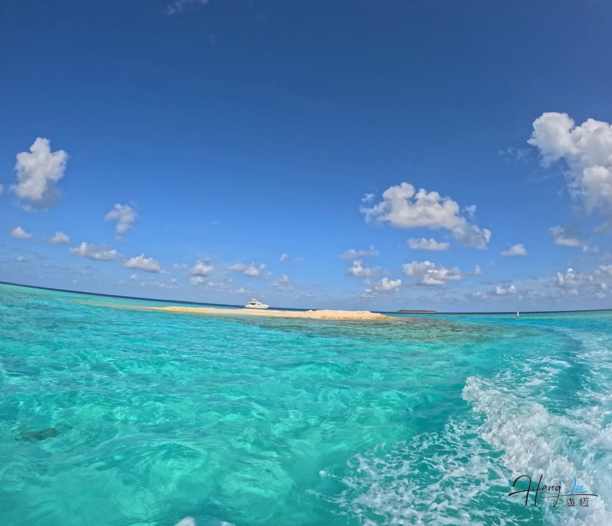 Turquoise Sea With Small Island And Boat Under Blue Sky