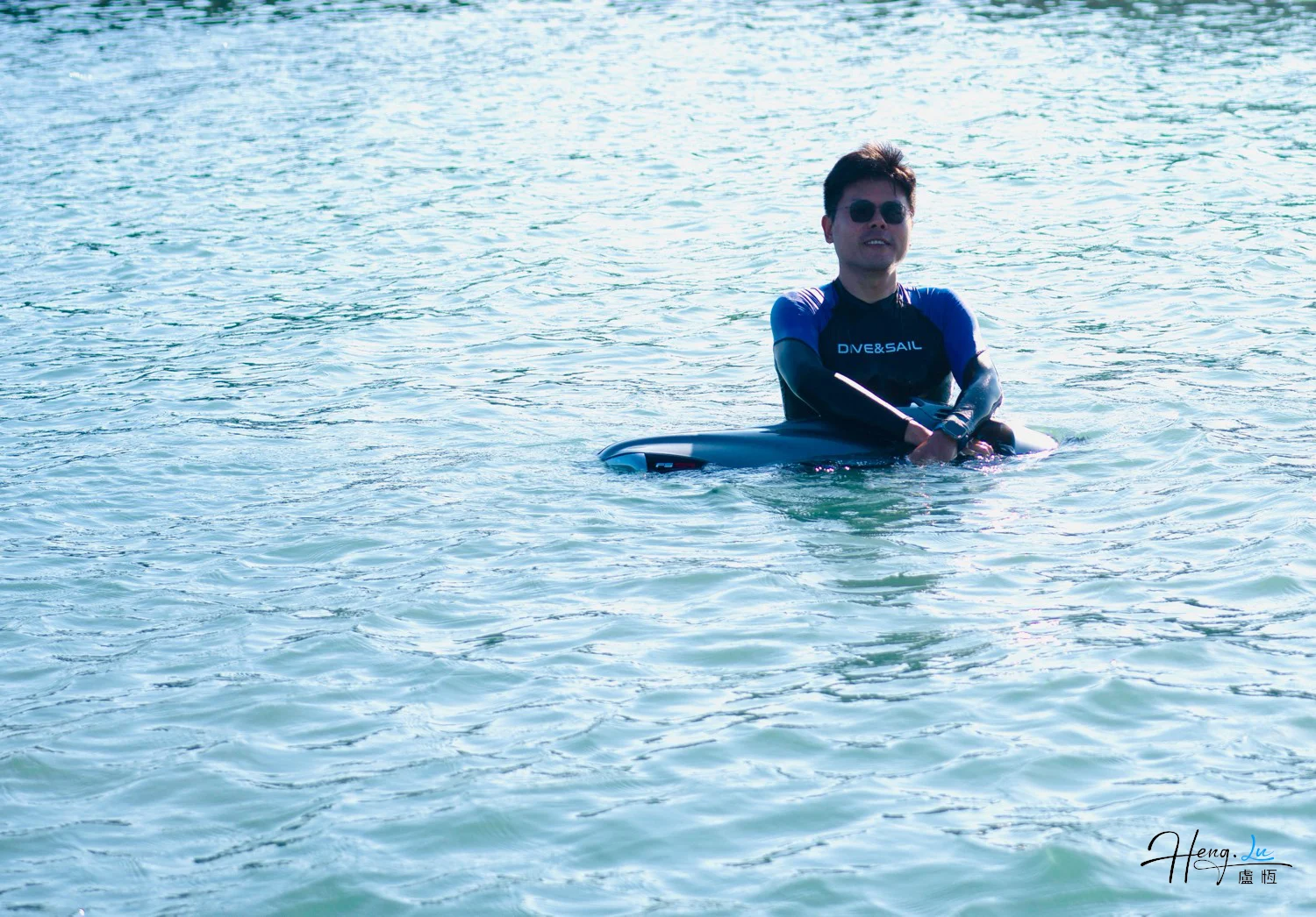 Luheng in Wetsuit Sitting on Paddleboard in Water