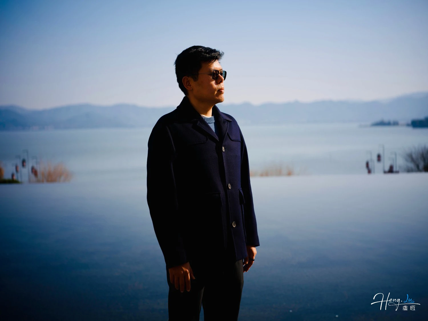 Lu Heng Standing by Lake Under Clear Blue Sky in Serene Landscape