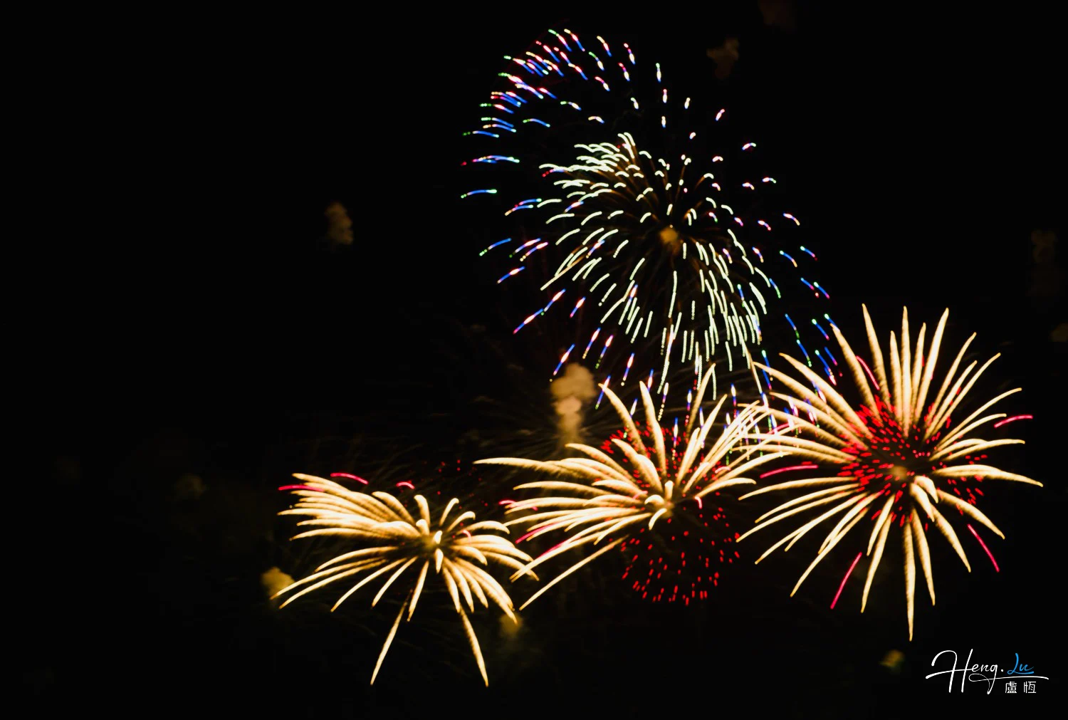 Gold and red fireworks bursting above dark sky