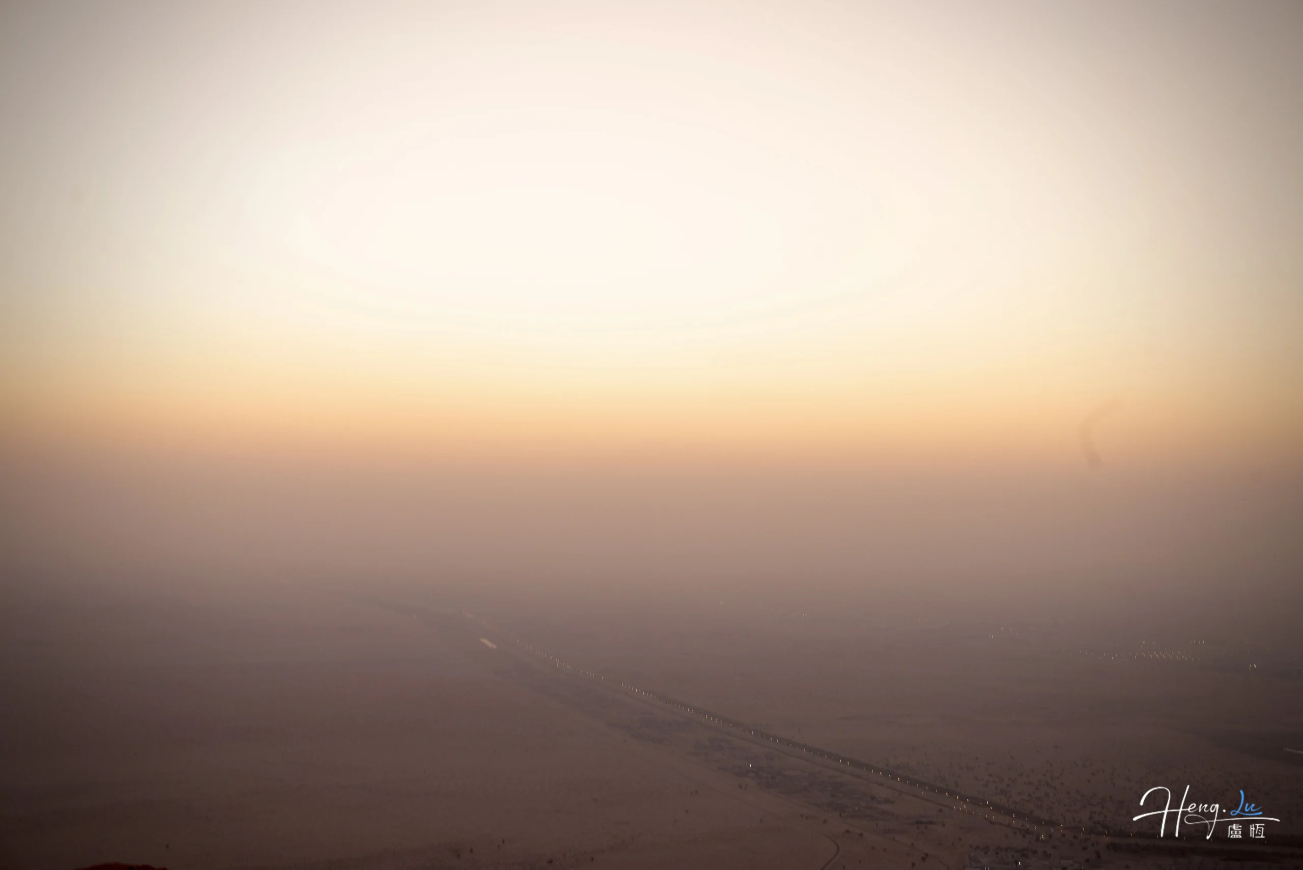 Desert horizon fading into warm sunset sky