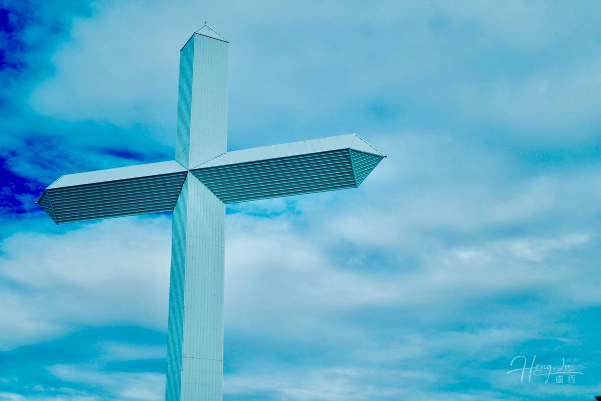 A Large Modern Cross Against A Blue Sky