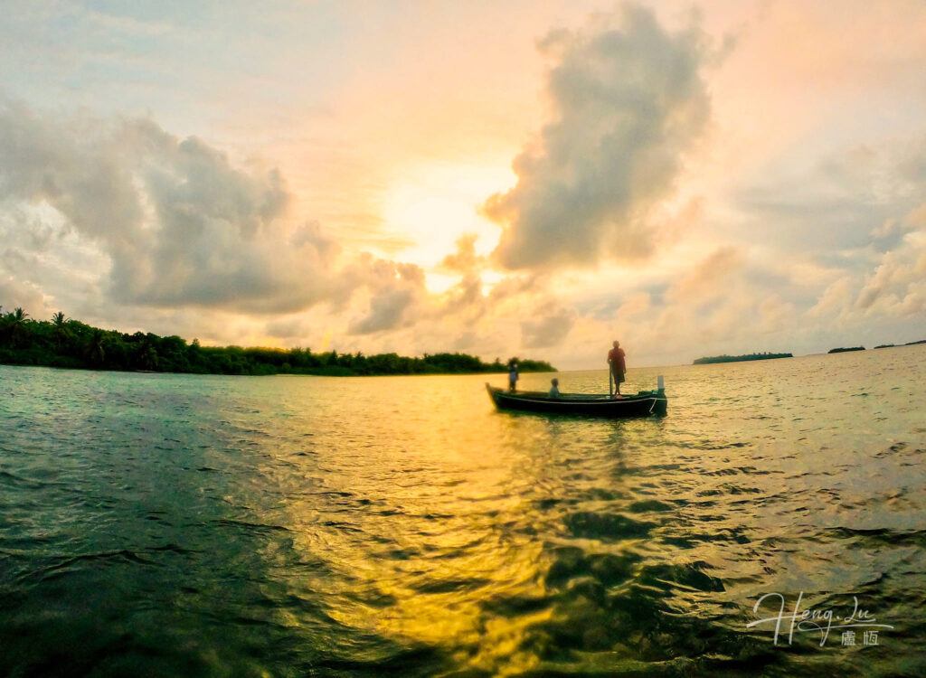 Boat at a golden sunset over a tranquil sea with clouds