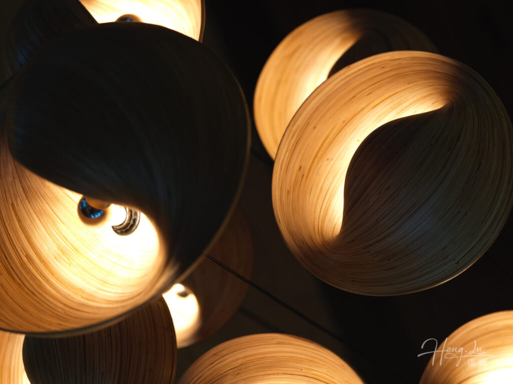 Warm glowing lamps with curved wooden shades in darkness