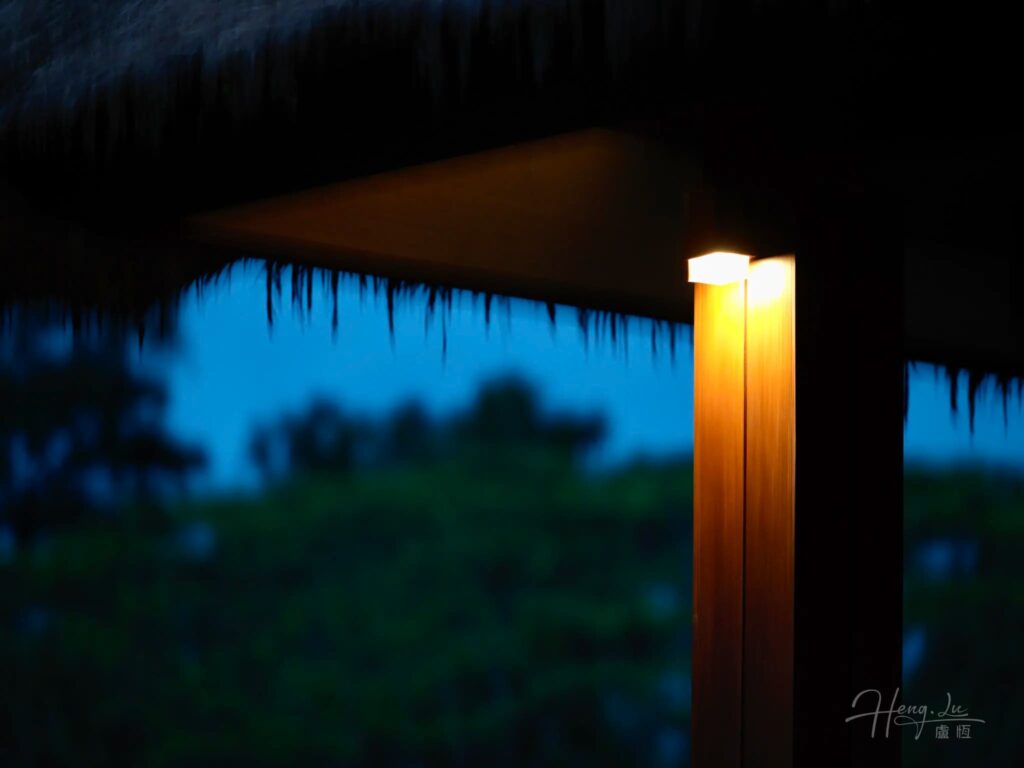 Warm light under thatched roof in evening blue