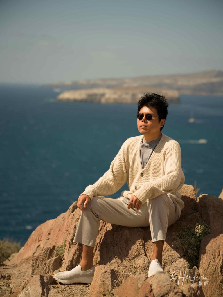 Luheng relaxing on coastal clifftop overlooking the deep blue sea
