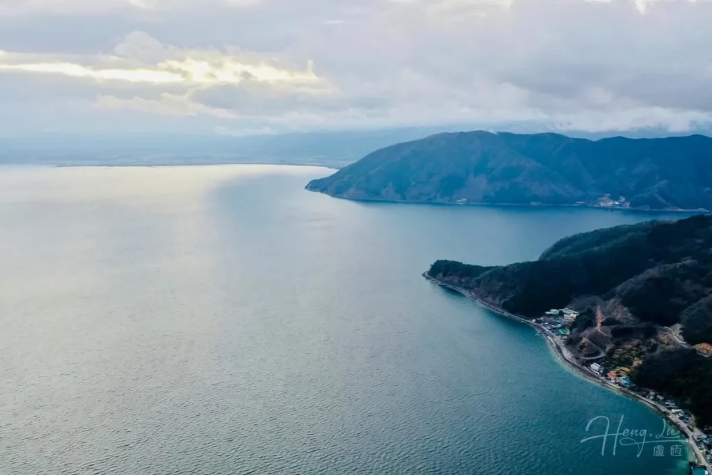 Mountain coast and calm sea under soft cloudy sky Aerial-view-of-a-Japan-lake-surrounded-by-mountains