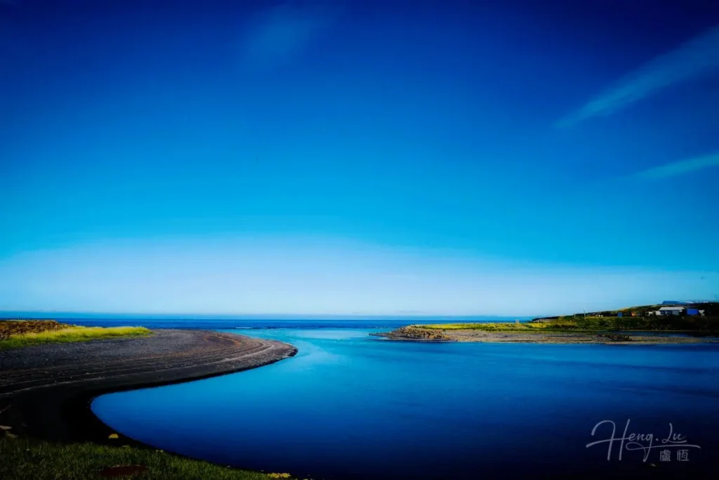Bright Blue Sky Over Calm River Bend with Coastline Curved-river-mouth-flowing-into-blue-sea-in-Iceland