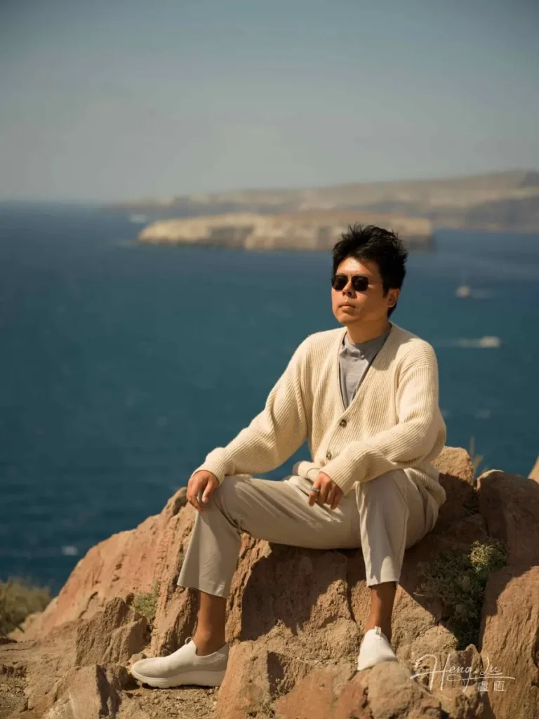 Luheng relaxing on coastal clifftop overlooking the deep blue sea Luheng-in-sunglasses-sitting-on-coastal-rock