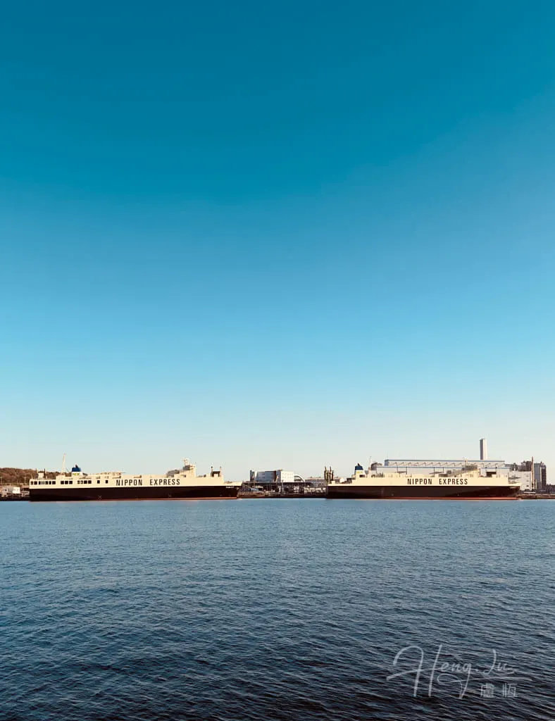 Cargo ships on calm sea under clear blue sky Two-Nippon-Express-cargo-ships-docked-near-industrial-port