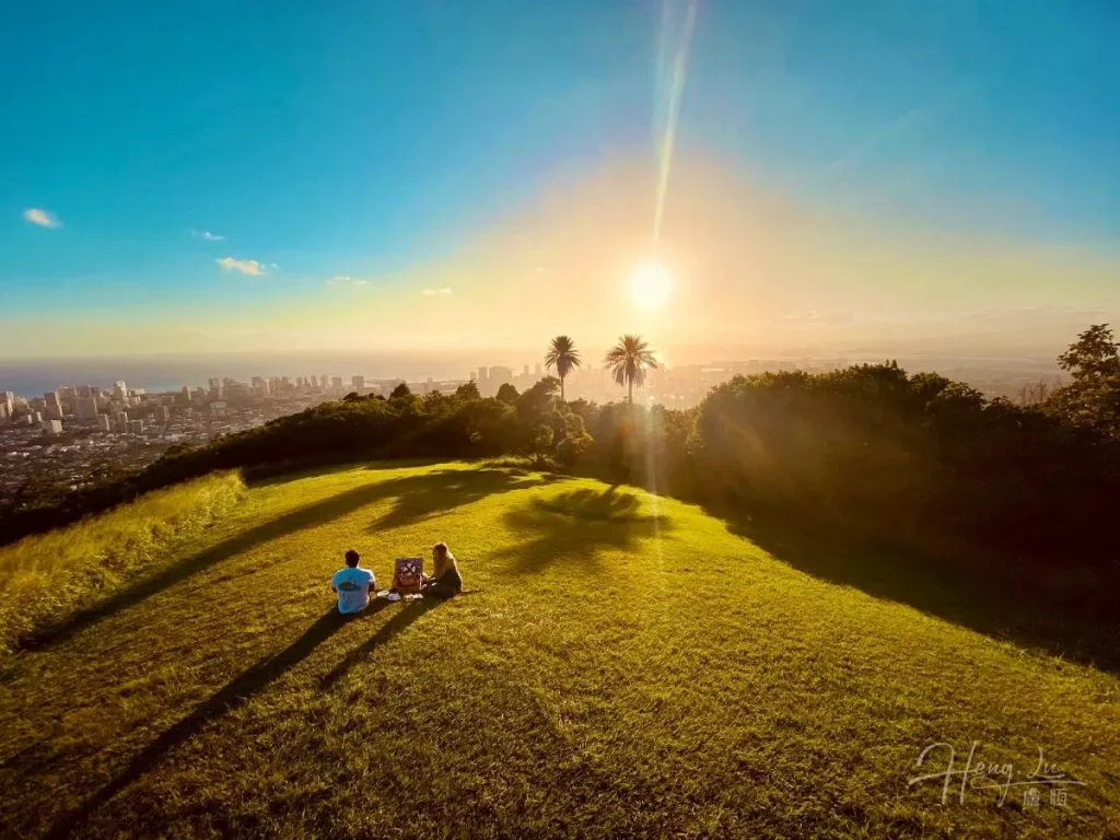 Picturesque Sunset Romance on a Hill Couple-sitting-on-green-hill-overlooking-city-sunset
