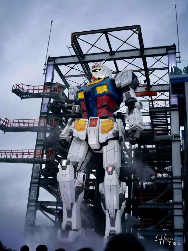 Large Gundam Robot Statue Under Cloudy Sky with Industrial Structure Large-gundam-robot