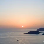Evening descent over calm waters Sunset-over-sea-with-islands-and-boat