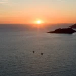 Golden Sunset Over Calm Sea with Boats and Coastal Island Sunset-over-sea-with-two-sailboats