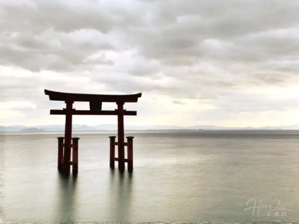 The Torii Gateway on the Shore in Japan Torii-gate-standing-in-calm-water-under-cloudy-sky