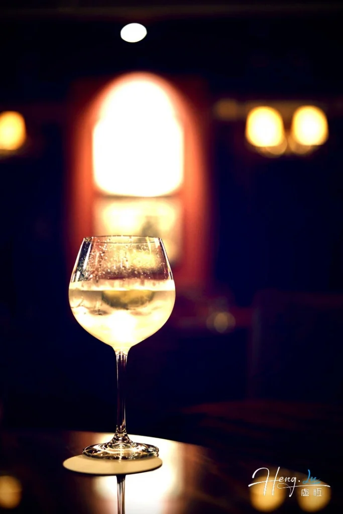 Light resting on the edge of night illuminated-wine-glass-on-bar-table-with-bokeh