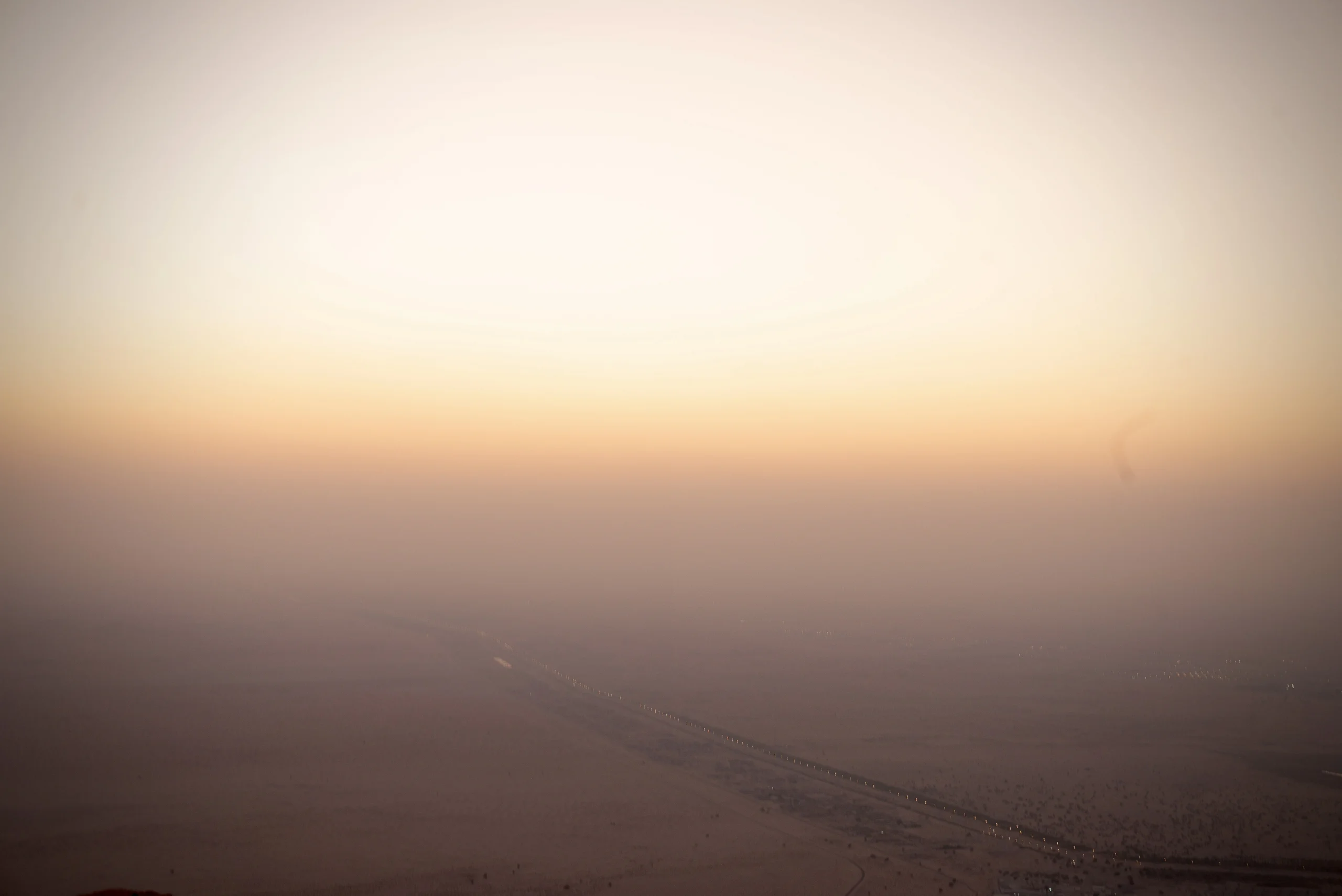 Desert horizon fading into warm sunset sky