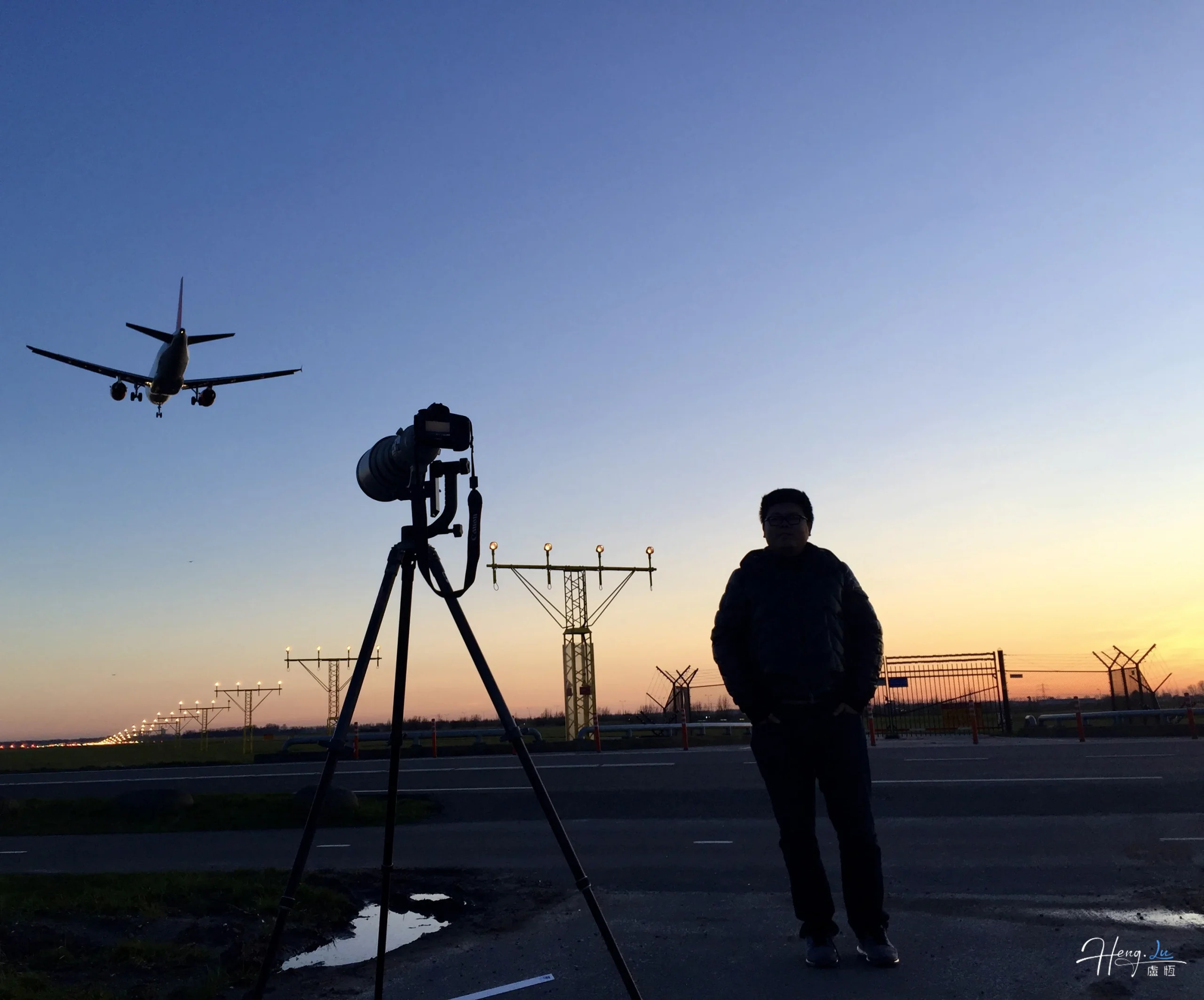 Photographer capturing landing plane during sunset
